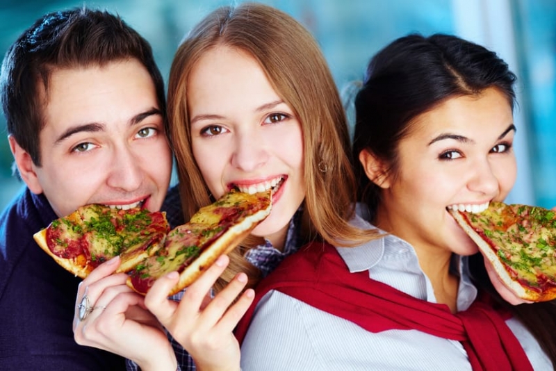 Group of young people eating pizza